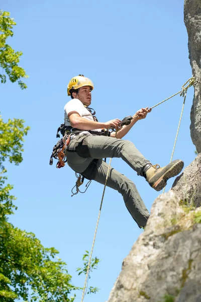 若い男は岩壁の登山 — ストック写真