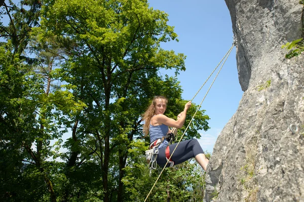 Young woman climbing a rock wall — Stock Photo, Image