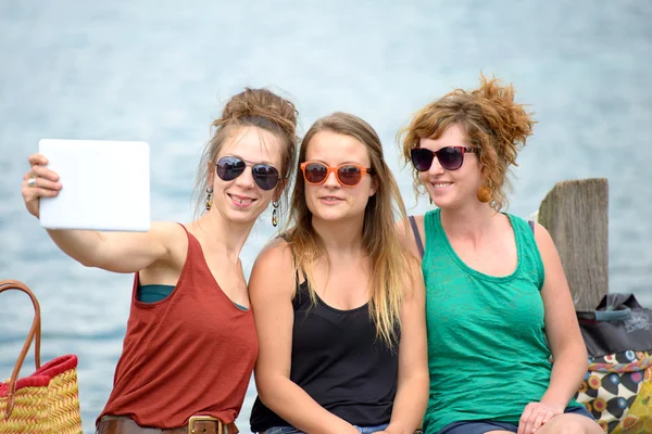 Drei junge Frauen am Strand mit ihrem digitalen Tablet — Stockfoto