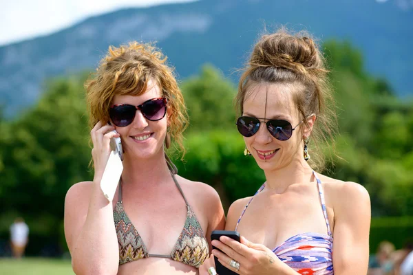 Two young women on the phone at the beach — Stock Photo, Image