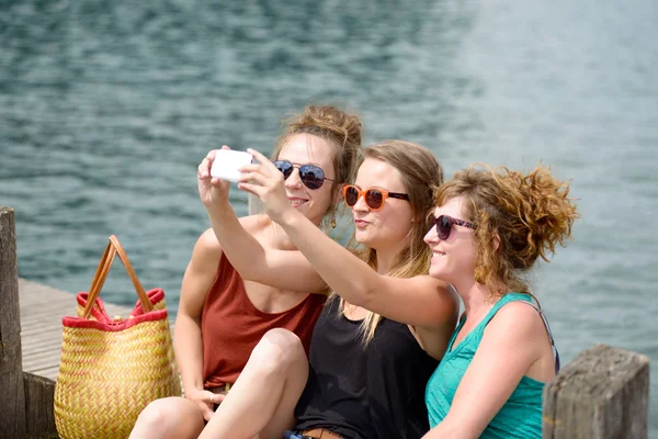 Drei junge Frau am Strand mit ihrem Handy — Stockfoto