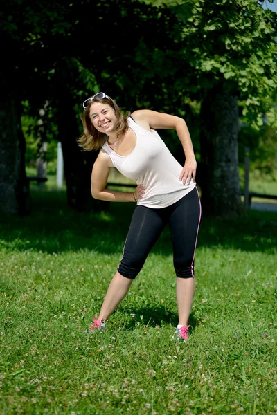 Sporty young woman makes stretching exercises — Stock Photo, Image