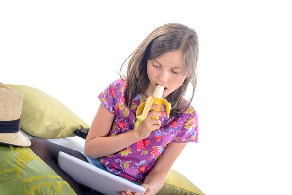 Écolière regardant une tablette numérique et manger des fruits — Photo