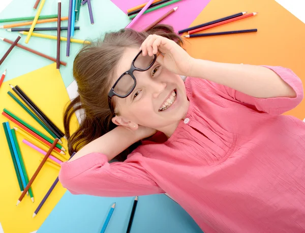 Школьница лежит на полу с цветными карандашами — стоковое фото