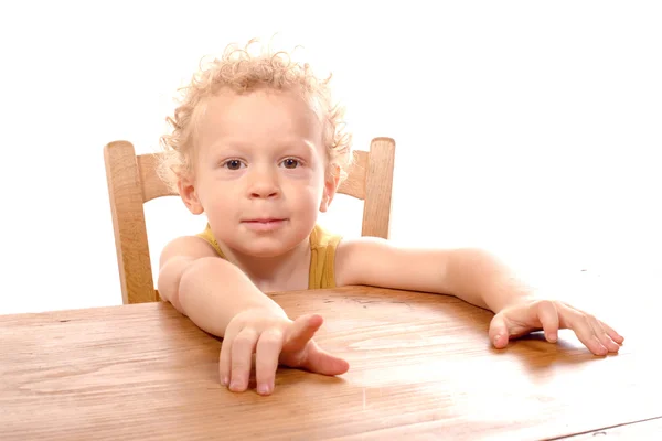 Pequena criança loira sentada à mesa — Fotografia de Stock