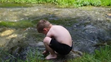 Küçük çocuk nehirde oynuyor.