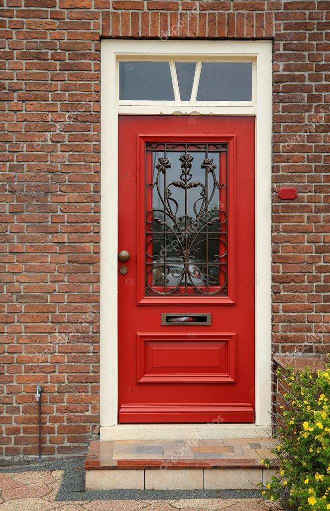 Red door with wroughtiron bars on the brick wall of a house — Stock