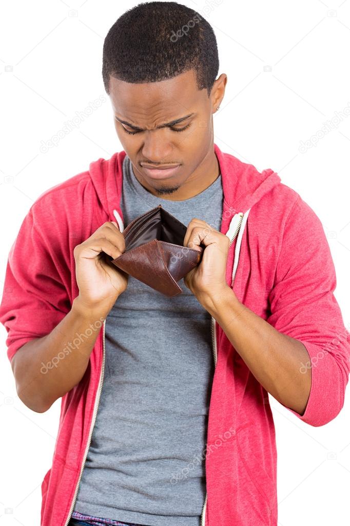 Closeup portrait of stressed, upset, sad, unhappy young man standing with, looking into empty wallet
