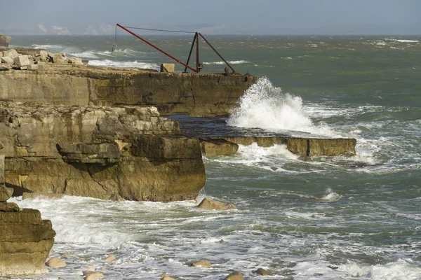 Crashing waves, rocks and a boat crane, Portland Bill — Stock Photo, Image