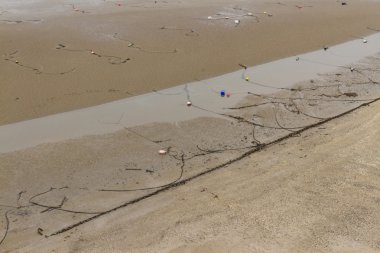 Zincirler, bağlama ipleri ve şamandıralar, düşük tide kumsalda.