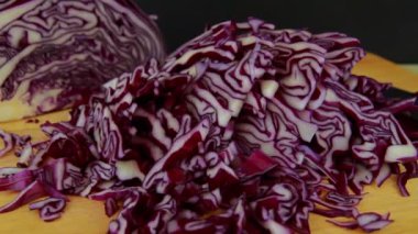 Tracking Video of Shredded red cabbage on a  chopping board with knife, panning left to right.