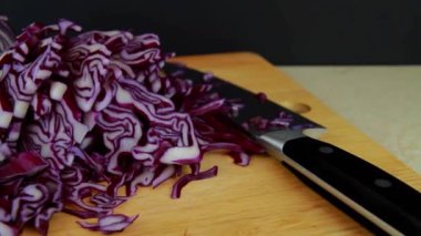 Tracking Video of Shredded red cabbage on a  chopping board with knife, panning right to left