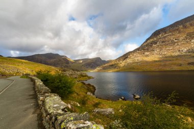 Lake or llyn Ogwen with mountain pen yr ole wen behind. With the Nant Ffrancon Pass, Bethesda, Snowdonia, North Wales, UK, wide angle, A5 road in foreground.