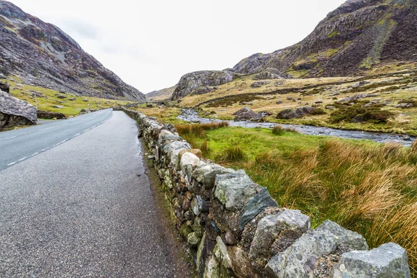 Magnificent Mountain Pass. The A4086 road and the Llanberis Pass. Snowdonia, Gwynedd, Wales, UK, landscape, stone wall in foreground