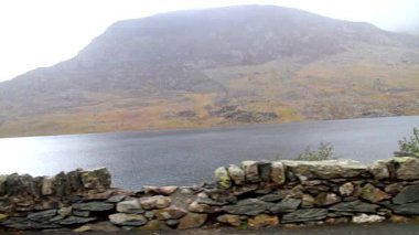 Video, pan as it from carLake or llyn Ogwen with mountain pen yr ole wen behind. With the Nant Ffrancon Pass, Bethesda, Snowdonia, North Wales, UK, wide angle, stone wall  in foreground.