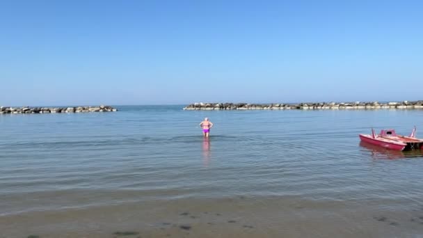 Riviera Adriatica. Donna anziana che cammina nel mare. — Video Stock