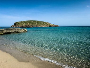 Sabahın erken saatlerinde Cala Compte plajında, Tago Mago 'nun küçük adası manzaralı. Kristal berrak su, turkuaz deniz, Akdeniz yaz cenneti.