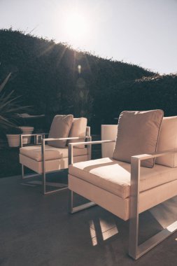 Şehir bahçesinde, özel ya da oteldeki beyaz koltuklu bir oturma alanının yakın çekimi.