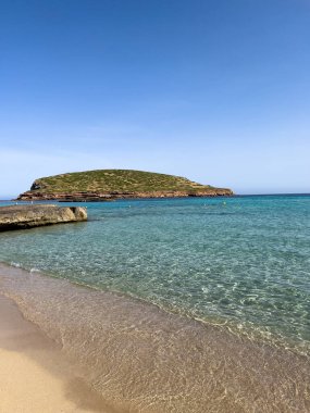 Sabahın erken saatlerinde Cala Compte plajında, Tago Mago 'nun küçük adası manzaralı. Kristal berrak su, turkuaz deniz, Akdeniz yaz cenneti.