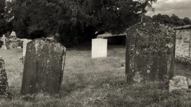 Burford, İngiltere, 29 Haziran 2022. St. Peters Kilisesi 'ndeki küçük, huzurlu ve ürkütücü mezarlıkta etrafa saçılmış mezar taşları ve yosunlu mezar taşlarıyla dolaşmak..