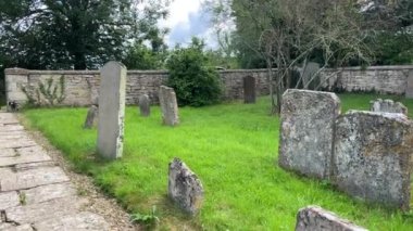 Burford, İngiltere, 29 Haziran 2022. St. Peters Kilisesi 'ndeki küçük, huzurlu ve ürkütücü mezarlıkta etrafa saçılmış mezar taşları ve yosunlu mezar taşlarıyla dolaşmak..