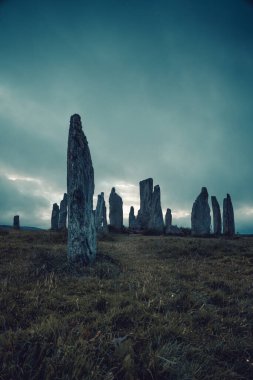 Ön taşa odaklan. Calanais Ayakta Kalan Taşlar Çemberi 'ndeki antik büyü neolitik adamlar tarafından ibadet için dikildi. İskoçya 'nın dış hebritlerinde Kelt gelenekleri. Turistik cazibe.