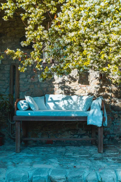 Paradise on earth, a wooden bed on a cobblestone porch in an Italian rustic country house, with rich jasmine plant, natural shade, relaxing spot.