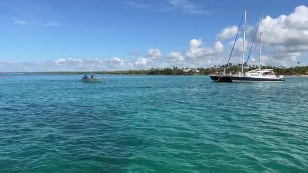 Bayahibe 多米尼加共和国 2022年8月16日 照相机漂浮在加勒比海的水面上 晶莹而蓝绿色 一条双鱼靠岸 一艘船经过 — 图库视频影像