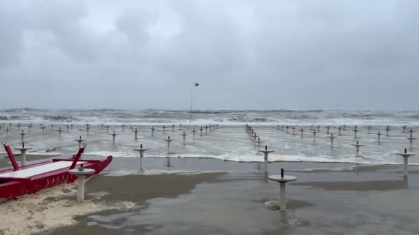 意大利亚得里亚海里维埃拉 罗马戈诺拉海滩上的一场海暴的广角镜 汹涌的大海 覆盖海滩的长波 威胁着天空 红色救生船在前方 — 图库视频影像