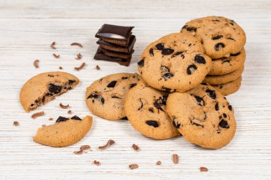 Çikolata parçalı, beyaz tahta bir masada lezzetli çikolatalı kurabiyeler..