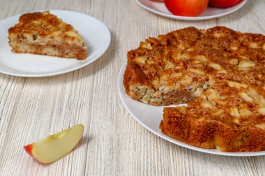 Elmalı turta ahşap bir masada kırmızı elmaların arka planına karşı..