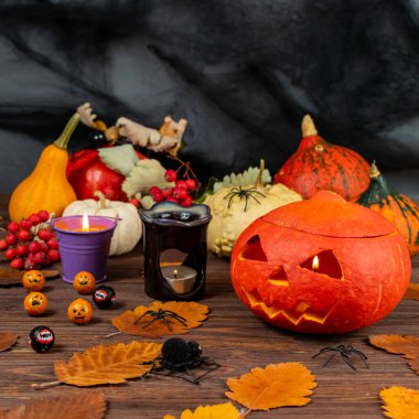 İçinde örümcekler, mumlar, balkabakları ve yapraklar olan ahşap bir masada Cadılar Bayramı balkabakları. Cadılar Bayramı temalı kavramsal natürmort hayat.