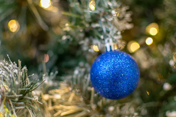 蓝色的球落在绿色的云杉树枝上，背景模糊不清。圣诞和新年装饰品。树上的一个小摆设浅水区深度 — 图库照片