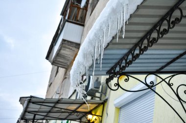 Eriyen donmuş kardan şeffaf buz sarkıtları balkonun çatısında yükselecek..
