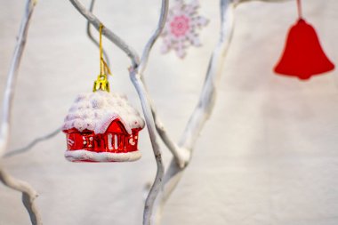 Kırmızı bir oyuncak cam ev beyaz bir dala asılı. Noel ve Yeni Yıl dekorasyonları, tasarım.