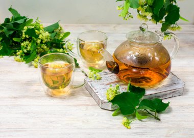 Çaydanlık ve ahşap bir masanın üzerinde ıhlamur ağacı olan iki fincan çay. Çay demliyorum..