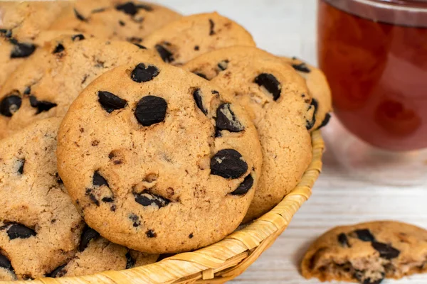 Biscoitos de chocolate em uma cesta no fundo de uma xícara de chá de vidro. Close-up. — Fotografia de Stock