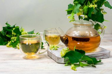 Çaydanlık ve ahşap bir masanın üzerinde ıhlamur ağacı olan iki fincan çay. Çay demliyorum..