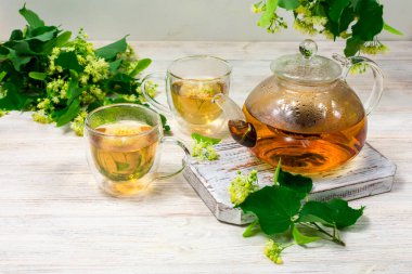 Çaydanlık ve ahşap bir masanın üzerinde ıhlamur ağacı olan iki fincan çay. Çay demliyorum..