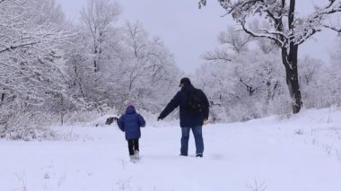 Dad and daughter go for a walk along a snowy road on a winter day.