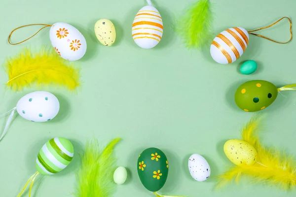 Marco de Pascua con huevos y plumas sobre un fondo verde. Concepto mínimo. Vista desde arriba. Tarjeta con espacio de copia para texto. — Foto de Stock