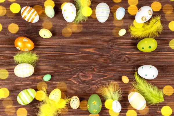 Wielkanocna rama z jajkami i piórami na ciemnym drewnianym tle z pasemkami. Widok z góry. Miejsce na tekst. — Zdjęcie stockowe