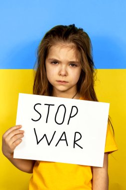 Bir kız ağlıyor, elinde Ukrayna bayrağının arka planında bir dur posteri var. Ukrayna 'daki savaşı durdurun. Ukrayna 'da barış kavramı.