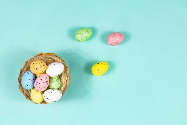 Œufs de Pâques multicolores dans un nid sur un fond bleu avec espace pour le texte, le lettrage. Base pour une carte postale, Vue du dessus. — Photo