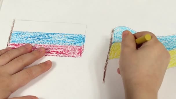 Les mains d'enfant d'un enfant tirent les drapeaux de l'Ukraine et de la Russie en gros plan. Vue d'en haut. Les enfants dessinent pour la paix en Ukraine. — Video