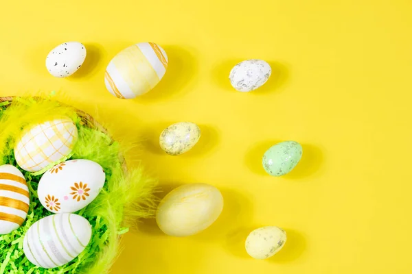 Nid de Pâques avec œufs et plumes sur fond jaune gros plan. Vue d'en haut. Endroit pour le texte. Concept minimal. — Photo