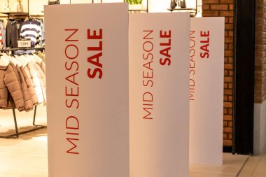 Alışveriş merkezinin girişindeki parlak beyaz reklam afişi. Mağazada mevsimlik indirimler