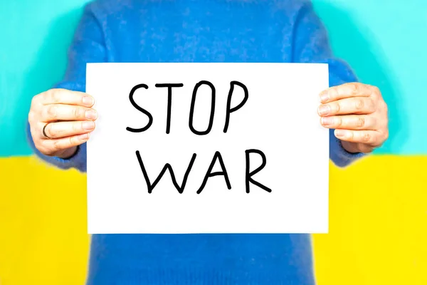 A woman holds a scarf with the inscription Stop the war on the background of the Ukrainian flag. Stop the war. — Stock Photo, Image