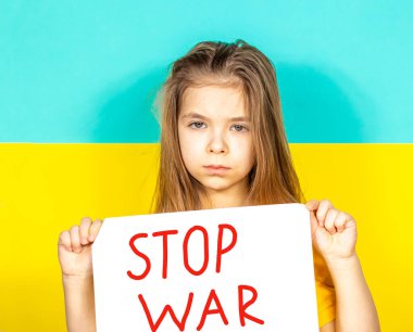 Bir kız ağlıyor, elinde Ukrayna bayrağının arka planına karşı bir savaş ilanı tutuyor..