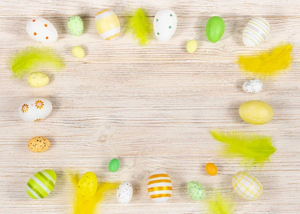 Marco de Pascua con huevos y plumas sobre un fondo de madera claro. Vista desde arriba. Tarjeta con espacio de copia para texto. — Foto de Stock